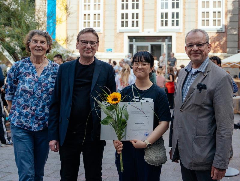 Michael Breda, Vizepräsident der Muthesius Kunsthochschule (rechts), Illustrations-Professor Markus Huber (2.v.l.) und Maud Zieschang vom International Office (l.) haben Hyeonah Kim die Auszeichnung überreicht.