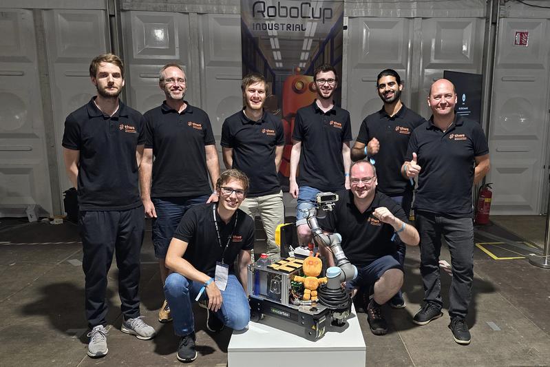 Team „SWOT“ mit ihrem Roboter und dem RoboCup-Maskottchen (v. li.): Julian Müller, Prof. Dr. Tobias Kaupp, Adrian Müller, Felix Endres, Lucas Reinhart, Martin Löser, Usama Ali und Stanislav Buinitskii 