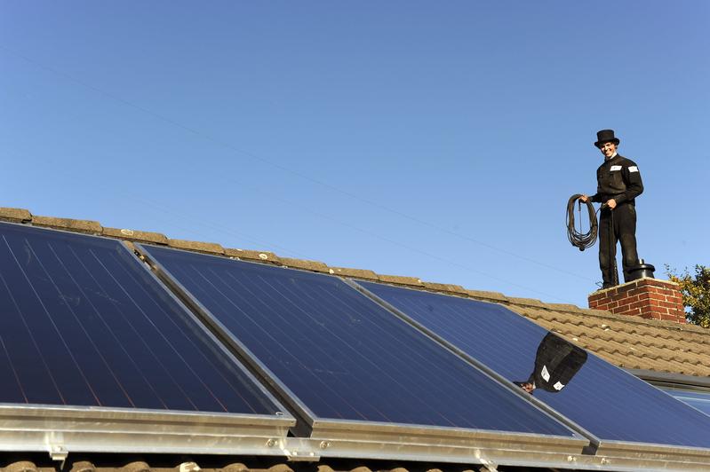 Ein Schornsteinfeger bei der Arbeit – mit dem Blick auf Solarmodule auf dem Dach. Die Deutsche Bundesstiftung Umwelt (DBU) hat in ihrer nationalen Info-Kampagne „Zukunft Zuhause – Nachhaltig sanieren“ viele Tipps parat. 