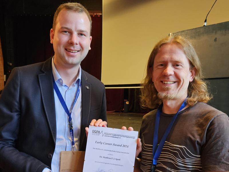 Prof. Dr. Matthias Gamer (r.), Vize-Präsident der DGPA e.V., überreicht Dr. Matthias Sperl den Early Career Award der Deutschen Gesellschaft für Psychophysiologie und ihre Anwendung.