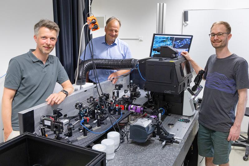 Dr. Rainer Kurre, Prof. Dr. Jacob Piehler und Doktorand Hauke Winkelmann vor dem Fluoreszenzmikroskop im CellNanOs.