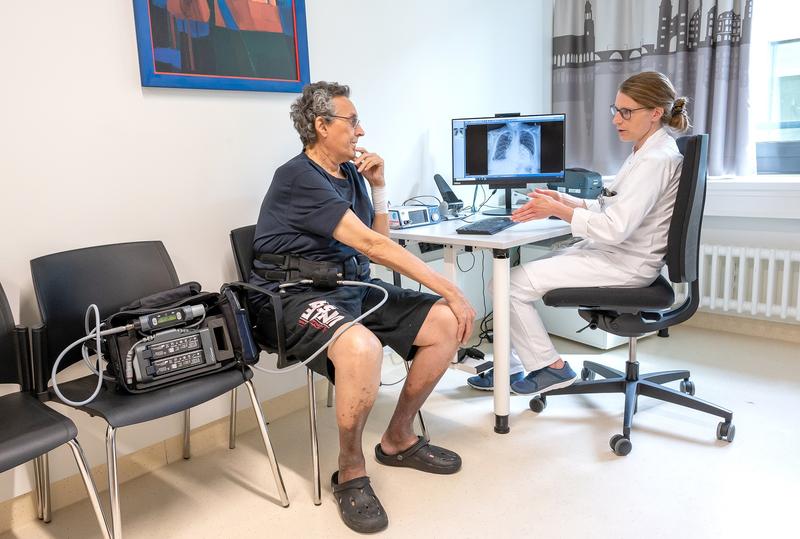 Die Leitende Oberärztin der Herzchirurgie am Universitätsklinikum Heidelberg, Prof. Dr. Anna Meyer, erläutert anhand des Röntgenbildes dem Patienten die Funktionsweise des Kunstherzens. Links im Bild ist die Tasche mit den Batterien zu sehen.