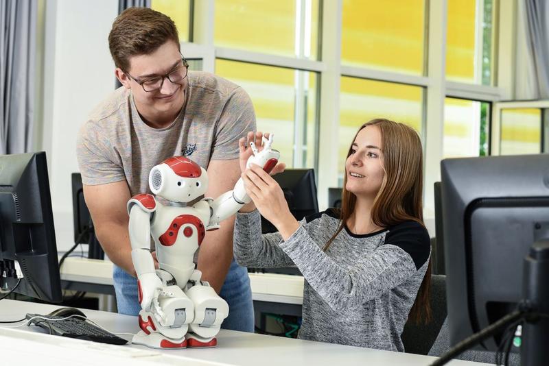 Studierende mit einem Roboter