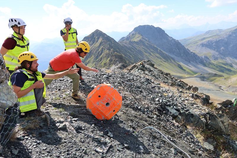The researchers push a custom-made concrete block down a debris-covered slope. In the experiment, they investigate how stones move down the slope.