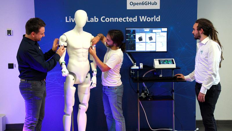 Jan Petershans (links), Robin Müller (Mitte), Christian König (rechts) richten den Funktionsdemonstrator ein, mit dem sie zeigen, wie die Aggregation von Gesundheitsdaten mittels 6G-Mobilfunk möglich werden könnte.