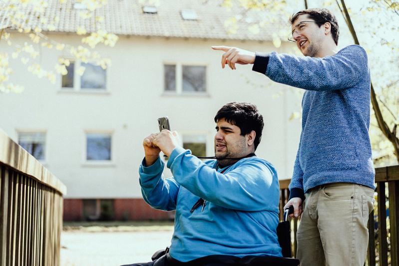 Enes Karabulut (links) und Dr. Konstantin Rink erkunden die Umgebung: Mit dem Trainingssystem auf dem Smartphone sollen sich Menschen mit kognitiven Einschränkungen möglichst selbstständig im öffentlichen Raum bewegen können.