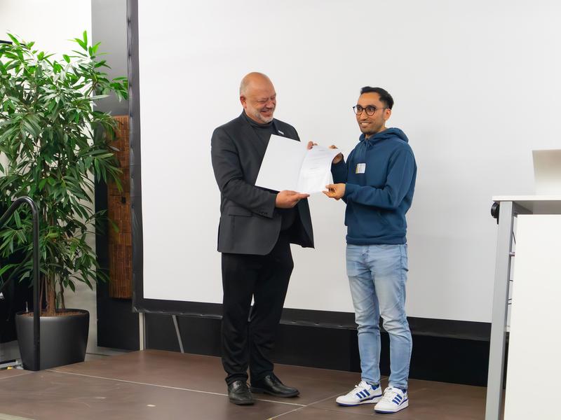 DAAD-Preisträger Bigyan Lamichhane (rechts) erhält seine Urkunde aus der Hand von h_da-Präsident Prof. Dr. Arnd Steinmetz.