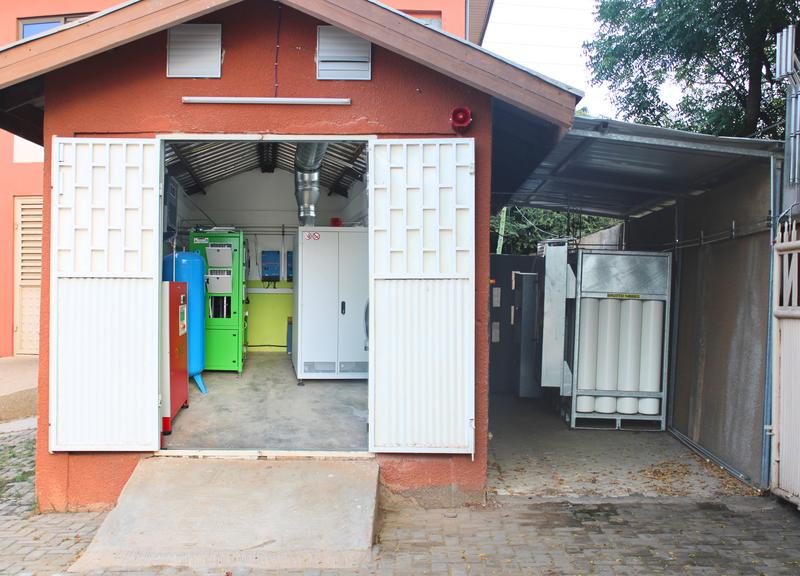 Aufbau des Wasserstoffsystems am Pilotstandort in Tema, Ghana. Links der Raum mit Elektrolyse und Brennstoffzelle, rechts außerhalb des Raumes die Wasserstoffspeicherung in 48 Druckgasflaschen, gestellt von der ostermeier H2drogen Solutions GmbH.