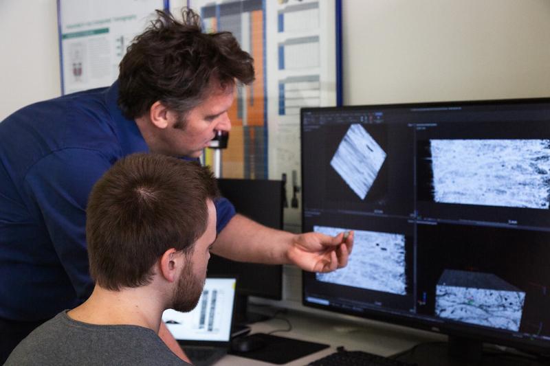 Forscher sehen am Bildschirm die Struktur eines vom Windenergie-Rotorblatt entnommenen Probekörpers in vielfacher Vergrößerung durch den Computertomographen. (v. l.:) Prof. Dr. Robert Böhm und Doktorand Philipp Johst