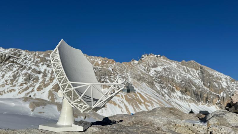 Modell des Wetterstein Millimeter Teleskops an einem der möglichen Standorte am Zugspitzplatt. Die Umweltforschungsstation ist im Hintergrund sichtbar, rund dreihundert Höhenmeter unterhalb des Gipfels der Zugspitze. 