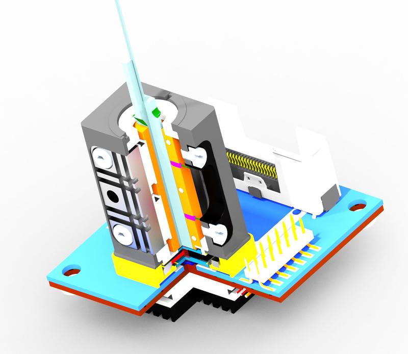 The VCSEL source on the ceramic printed circuit board (PCB) is shown with the KOVAR frame housing. The tiny glass tip on top of the housing is the waveguide combiner, where the polarization signal comes to exit.