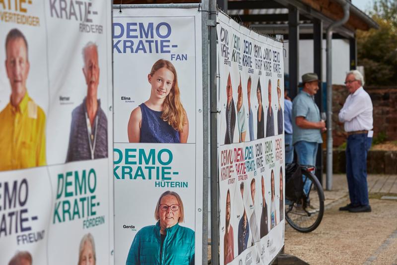 Plakate vergangener Fotoaktionen an einem Bauzaun