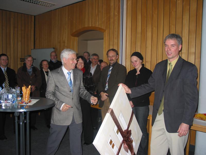 der Präsident der Hochschule Fulda, Pro. Dr. Roland Schopf (links) überreicht Volker Stempel (rechts) zum Abschied ein Gemälde