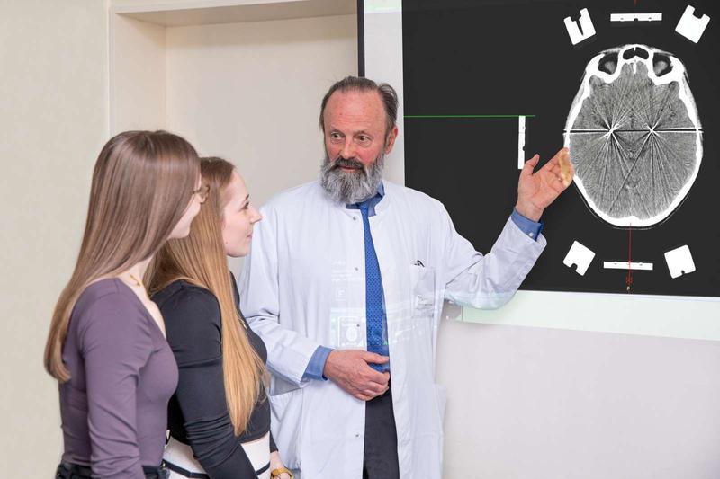 Professor Krauss looks at the image of a brain with Jette (left) and Nele. The electrodes of the neurostimulation system are visible as white dots. 