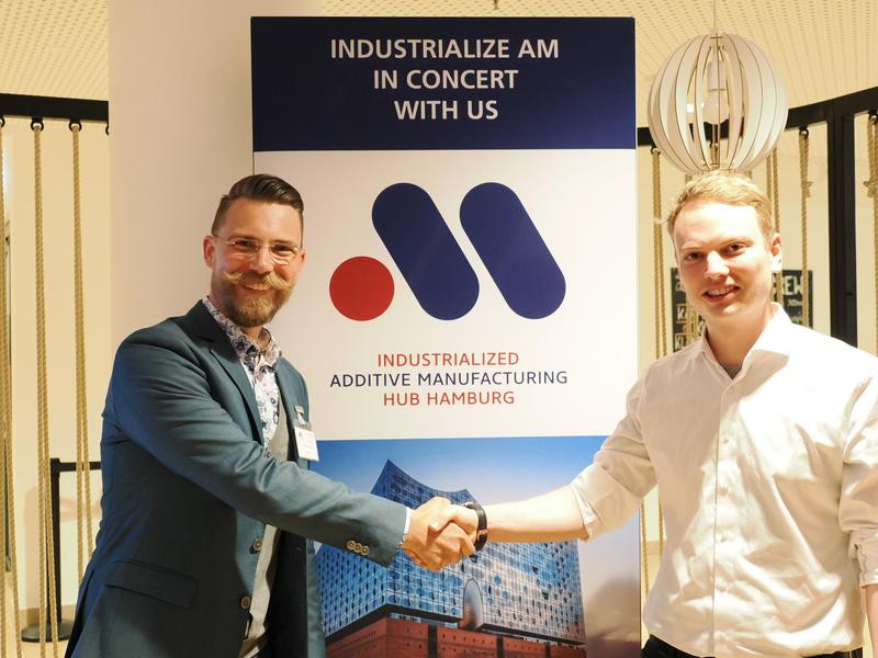 Dr. Maximilian Heres, Geschäftsführer des Industrialized Additive Manufacturing Hub Hamburg – IAMHH e.V., gratuliert Florian Aigner, CEO & Founder von Advanced Additive und Gewinner der AM Pitch Night