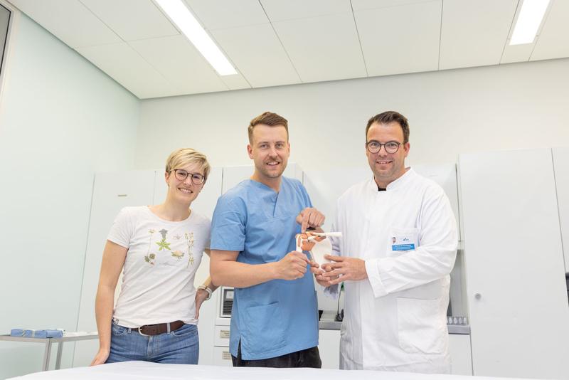 v.l.n.r.: Dr. rer. nat. Magdalena Elsner (Studienmanagement), Dr. med. Leopold Henßler (stellvertretende Studienleitung), Prof. Dr. med. Maximilian Kerschbaum (Studienleitung) zeigen am Modell die lange Bizepssehne. 