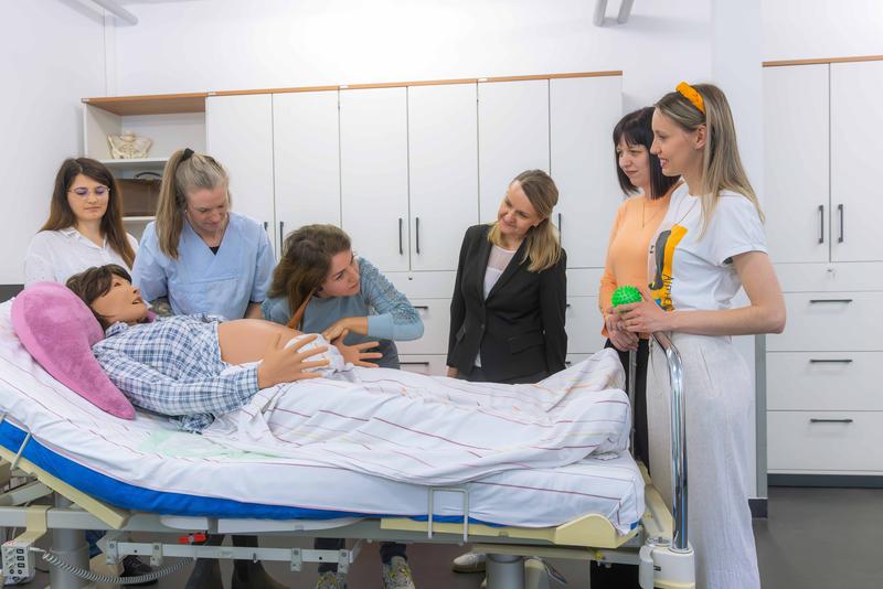 Eine Teilnehmerin übt am künstlichen Babybauch.