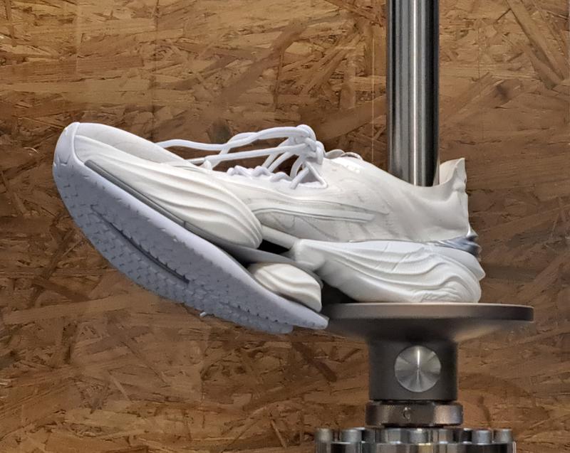 Einer der getesteten Sportschuhe in der Prüfmaschine beim Messen der Dämpfung am Fersensegment.