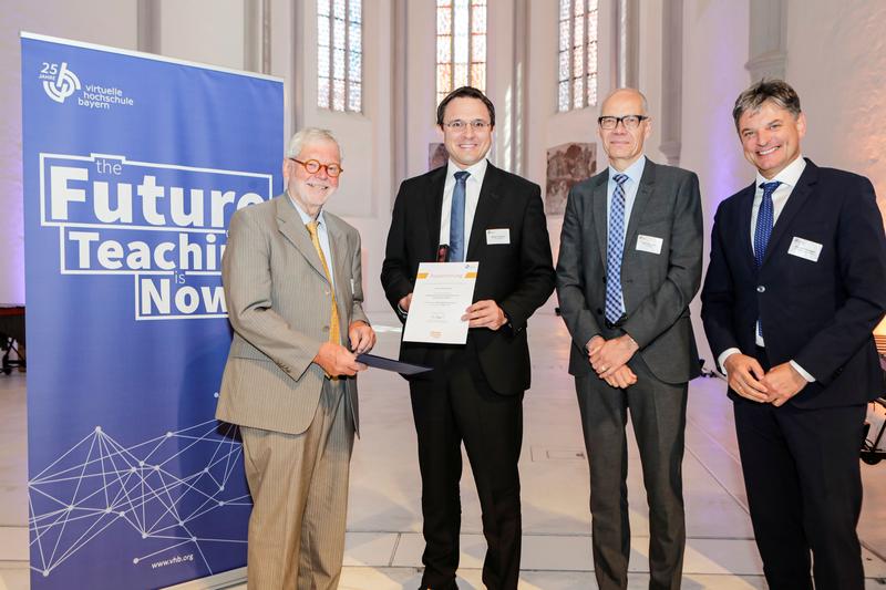Das Präsidium der Virtuellen Hochschule Bayern (Prof. Dr. Dr. habil. Godehard Ruppert (l), Prof. Dr. Niels Oberbeck (2. v. r.) und Prof. Dr. Joachim Hornegger (r.)) überreicht Prof. Dr. Markus Westner (2. v. l.) die Urkunde im Rahmen des vhb-Festakts.