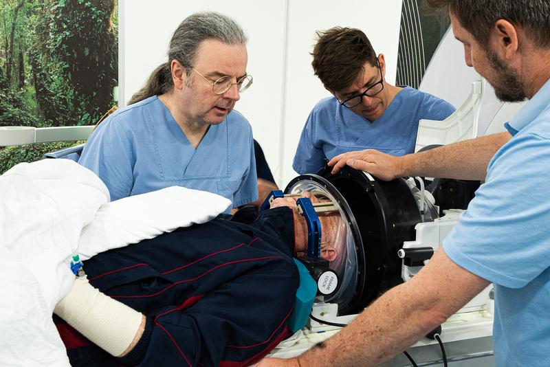 Prof. Coenen (links) und Dr. Sajonz (Mitte) prüfen ein letztes Mal die korrekte Positionierung des Patienten, bevor die fokussierte Ultraschall-Behandlung losgeht. 
