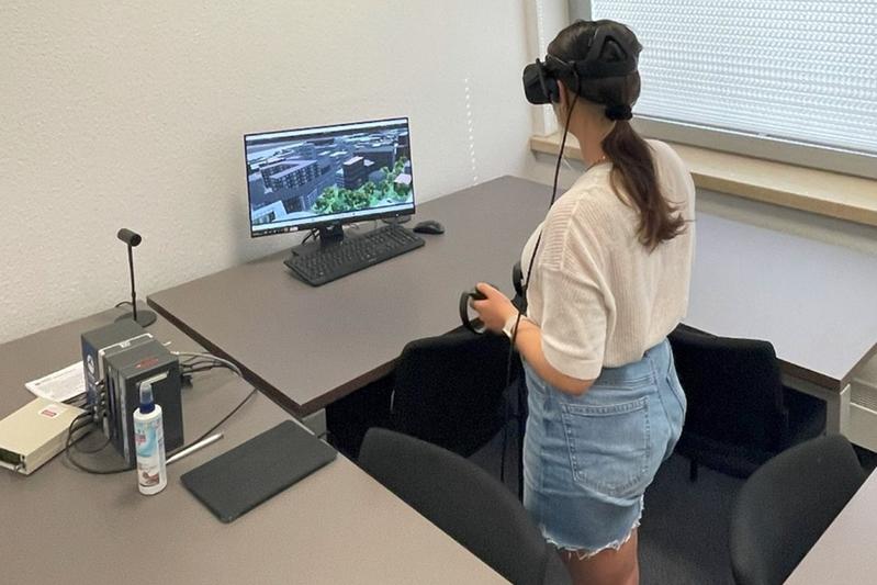   Das virtuelle Höhenszenario wird über eine Virtual-Reality Brille präsentiert, die auf den Kopf aufgesetzt wird. Die Teilnehmenden bewegen sich selbstständig durch das virtuelle Szenario mithilfe von handlichen Controllern. 
