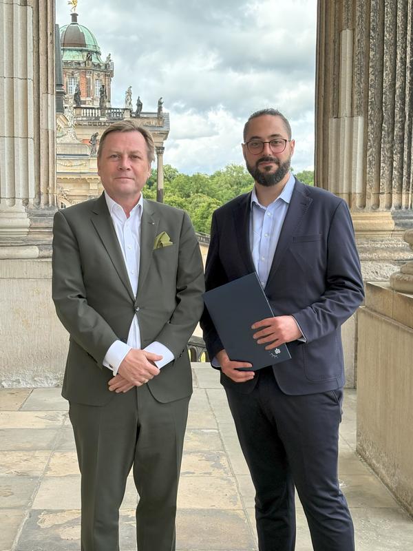 Prof. Oliver Günther, Ph.D. (l.) überreicht das Einweisungsschreiben an Prof. Dr. Jan Sürmeli.
