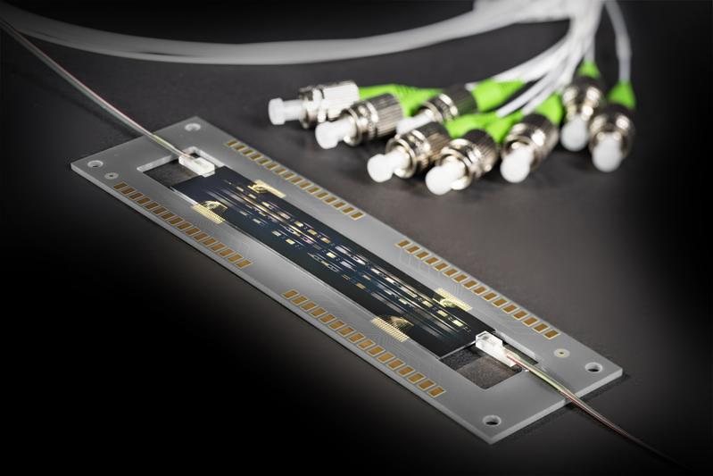 Integrated optical circuit with fiber optic connections (top and bottom). The modulator  signals are fed in via the gold electrodes on the sides.