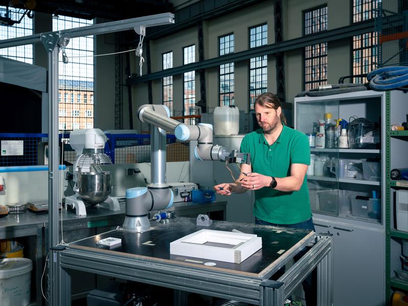 Mit diesem kleinen Roboterarm erforschen Timo Hartmann und sein Team, wie einglasige Fenster demontiert und zu mehrglasigen Fenstern wieder zusammengesetzt werden können. Der Roboterarm steht in der Peter-Behrens-Halle der TU Berlin.