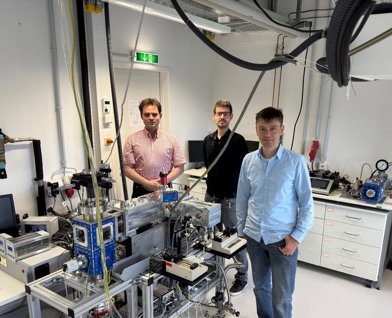 Die Leipziger Autoren des Übersichtsartikels: Prof. Dr. Jonas Warneke (links), Dr. Markus Rohdenburg (Mitte) und Dr. Harald Knorke (rechts) neben einem Instrument zur Synthese dünner Schichten mit gasförmigen geladenen Molekülbruchstücken.