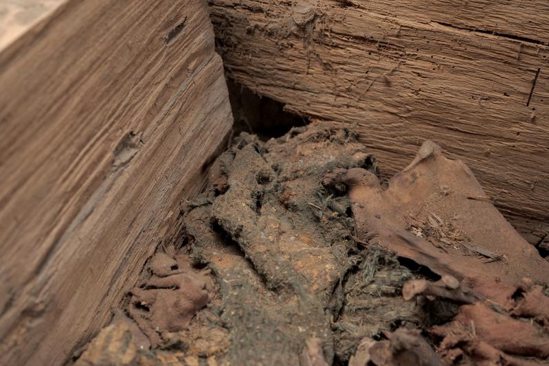 A view of the interior of the wooden coffin. The remains of high-quality textiles are clearly visible.