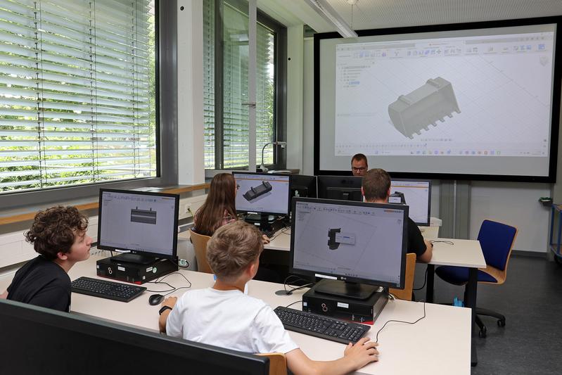 Im CAD-Labor der Fakultät Maschinenbau erläutert Mitarbeiter Max Pfennig das Design einer Baggerschaufel