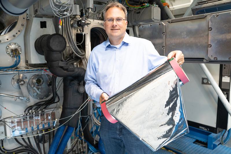 Projektleiter Claus Luber zeigt das Muster einer mittels Elektronenstrahlverdampfung mit Aluminium beschichteten Kunststofffolie