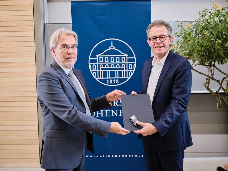 Georg Wacker (r.), Geschäftsführer der Staatlichen Toto-Lotto GmBH BaWü, erhält die Ehrennadel der Universität Hohenheim aus der Hand von Prorektor Prof. Dr. Andreas Pyka.
