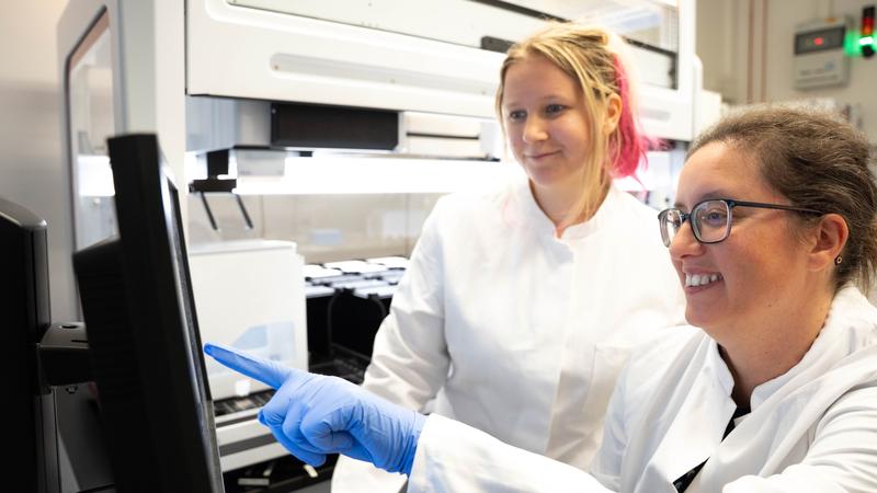 Die Wissenschaftlerin Ana Rita Brochado (rechts) und ihre Labormitarbeiterin Laura Sniegula blicken auf die Daten des Pipettierroboters. Mit diesem Laborgerät untersuchte das Team die Wirkung von 94 verschiedenen Substanzen.