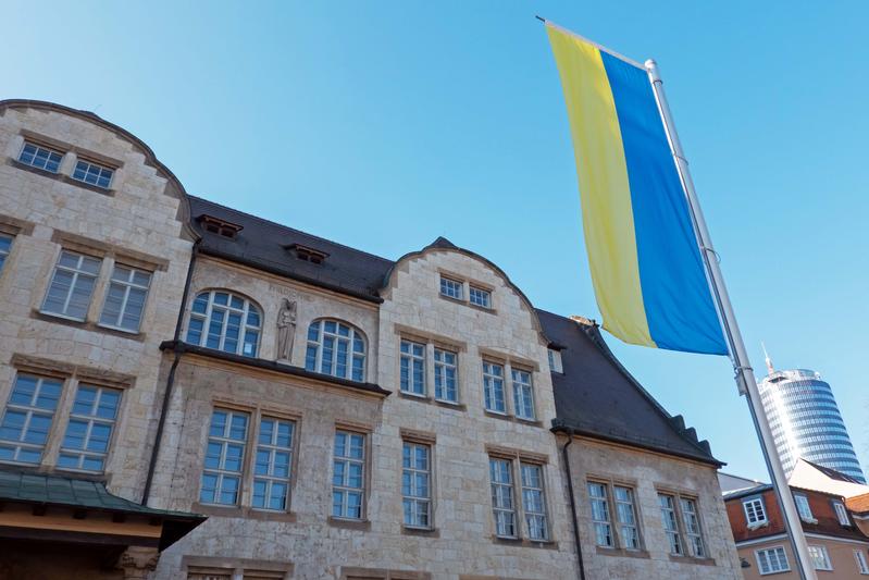 Eine ukrainische Flagge vor dem Jenaer Universitätshauptgebäude – Symbol für die enge Kooperation zwischen der Friedrich-Schiller-Universität und ihren ukrainischen Partnern.