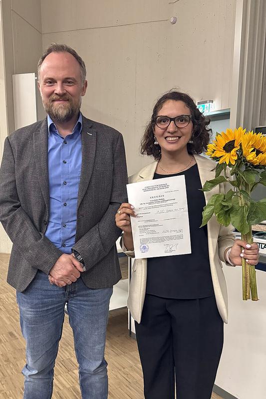 Nach der erfolgreichen Verteidigung: Promotionsstipendiatin Dalia Mahdy (re.) präsentiert gemeinsam mit ihrem Betreuer Prof. Dr. Jan Hansmann ihre Promotionsurkunde 
