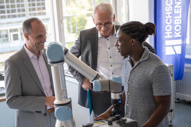Verschafft sich einen Eindruck vom Robotiklabor der Hochschule Koblenz: Wissenschaftsminister Clemens Hoch zum Start seiner Sommerreise 2025, hier mit Prof. Dr. Karl Stoffel, Präsident der Hochschule Koblenz und Student Fadou Ouro-Djeri (v.li.n.re.)