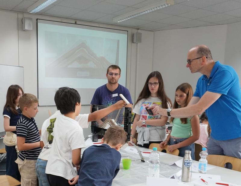 Dr. Eduard Harms erklärt Kindern beim SommerKinderCollege an der DHBW Karlsruhe, was beim Ausbruch eines Vulkans geschieht.
