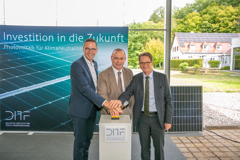 The mayor of Denkendorf, Ralf Barth, DITF Chairman Professor Michael R. Buchmeiser, and Permanent Secretary Michael Kleiner (from left) press the start button for the new photovoltaic system