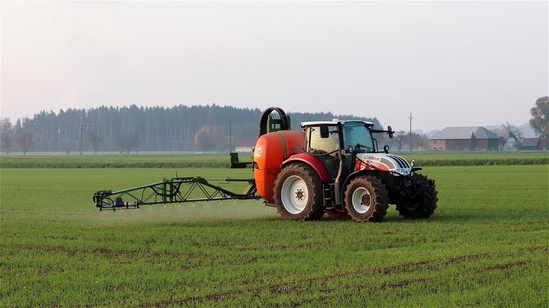 Traktor spritzt Pflanzenschutzmittel auf ein Feld