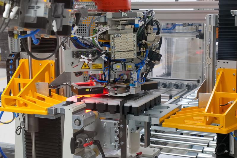 Die Stacking-Anlage der Referenzfabrik.H2: Hubeinheit für Stapel (orange), Werkstückträger mit Führungen (Mitte), Transfersystem, Greifer mit Fließsauger, Abstreifer und zwei Kameras zur Lagekorrektur.