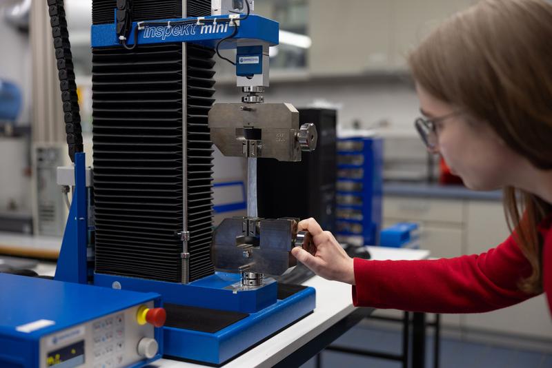 Für den Zugversuch im Labor für Biomechanik spannt die Doktorandin und wissenschaftliche Mitarbeiterin Julia Schneider das Material in die Probenhalter einer Zugprüfmaschine ein.