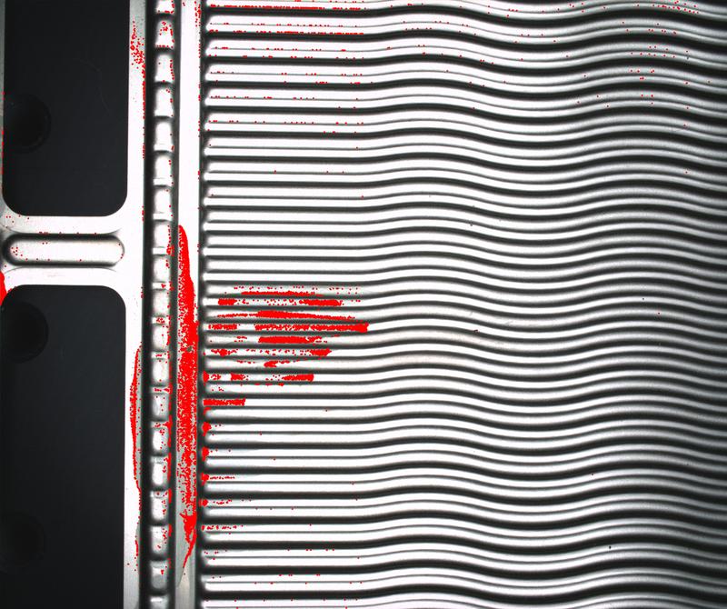 Kameras und eine Bildverarbeitungssoftware prüfen die einzelnen Komponenten eines Elektrolyseurs, bevor sie verbaut werden. In diesem konkreten Fall sind die rot markierten Verschmutzungen auf der Bipolarplatte zu groß. Sie wird aussortiert.