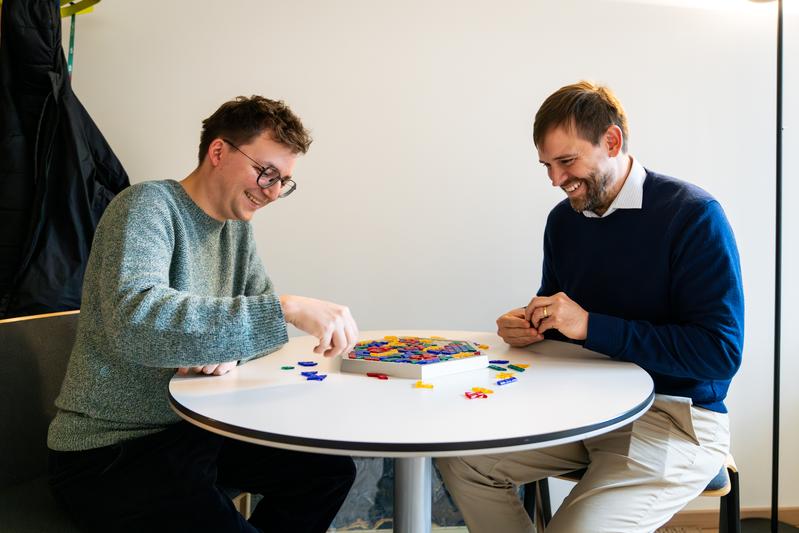 ISTA physicists created a ‘theoretical rulebook’ of self-assembly. The study’s first author, PhD student Maximilian Hübl, and Assistant Professor Carl Goodrich manipulate a simplified toy model while discussing their findings. 