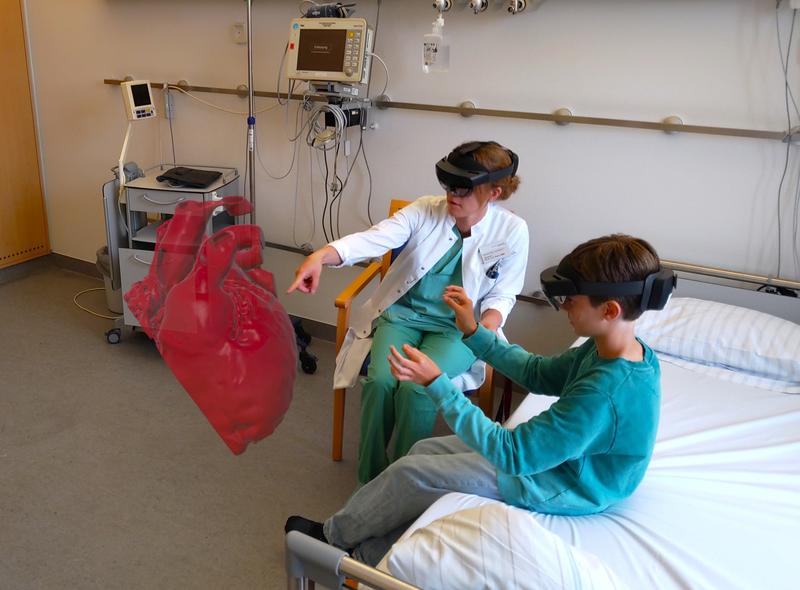 Ein Kind und eine Wissenschaftlerin des HoloHeart-Projekt-Teams im Uniklinikum Heidelberg beim Testen der HoloHeart-Software am Modell eines Kinderherzens.