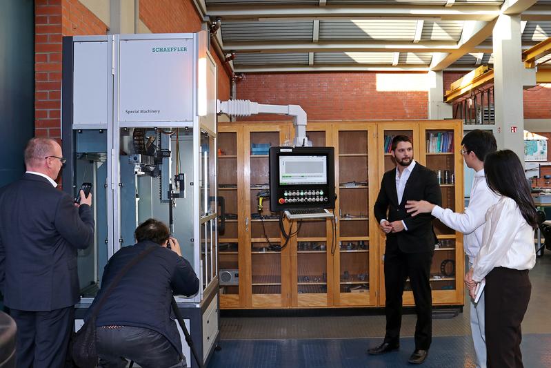 Wissenschaftlicher Mitarbeiter Dominik Stephan (3. v. re.) und Prof. Dr.-Ing. Stephan Sommer (li.) zeigen dem koreanischen Fernseh-Team die zerstörungsfreie Prüfanlage, in der Wälzlager getestet werden