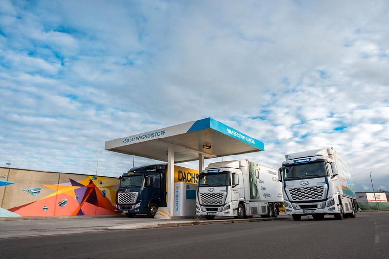 Visualisierung von drei Lastwagen, die an einer Wasserstofftankstelle stehen