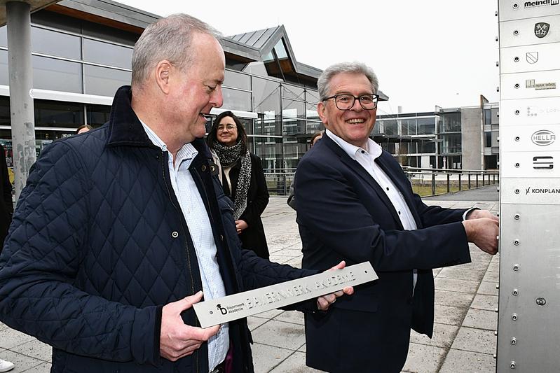 Albert Zettl (rechts), Personal- und Marktvorstand der Bayernwerk AG, befestigte das neue Schild der Bayernwerk Akademie an der Stifter-Stele.