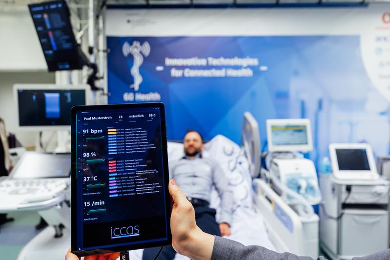 Auf einem Tablet werden drahtlos per Funkwelle die aktuellen Vitaldaten und Patienteninformationen angezeigt, sobald Ärzt:innen oder Pfleger:innen an ein Krankenbett treten.