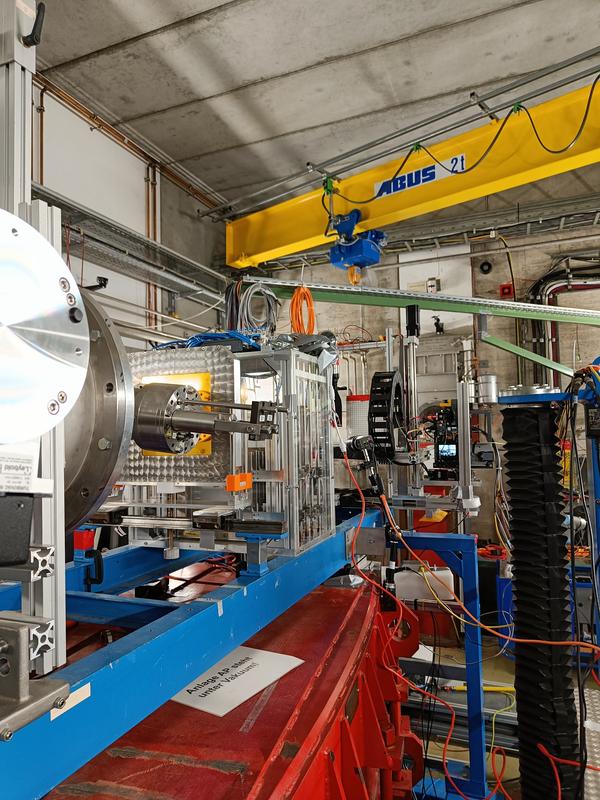 Experimental setup for the Nikon Z9 camera test at GSI/FAIR – In the front (left), the beam pipe is visible, followed by beam monitors (silver chamber with gold foil). In the background, the electronics test station with the mounted Nikon Z9 camera.